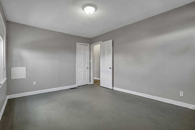 unfurnished bedroom with a textured ceiling, baseboards, visible vents, and a closet