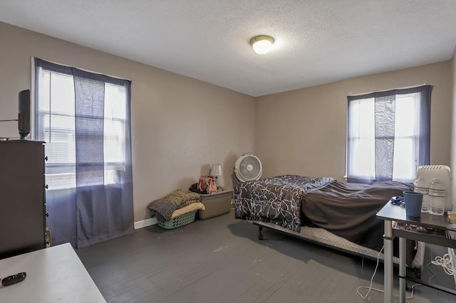 bedroom with a textured ceiling, multiple windows, and wood finished floors