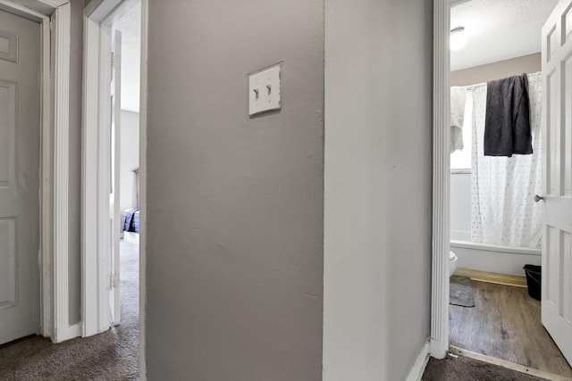 hall with baseboards, dark wood-style floors, and dark colored carpet