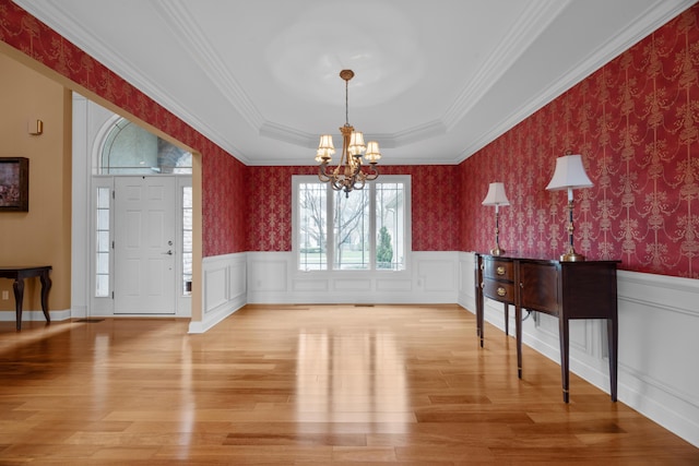 6700 Ballantrae Pl, Dublin, OH 43016 - foyer entrance featuring crown molding, an inviting chandelier, a wainscoted wall, a tray ceiling, and light wood-style flooring