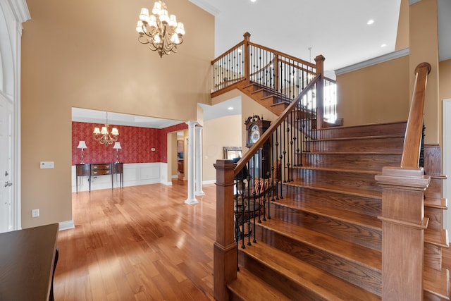 6700 Ballantrae Pl, Dublin, OH 43016 - staircase with a high ceiling, ornate columns, wood-type flooring, crown molding, and a notable chandelier