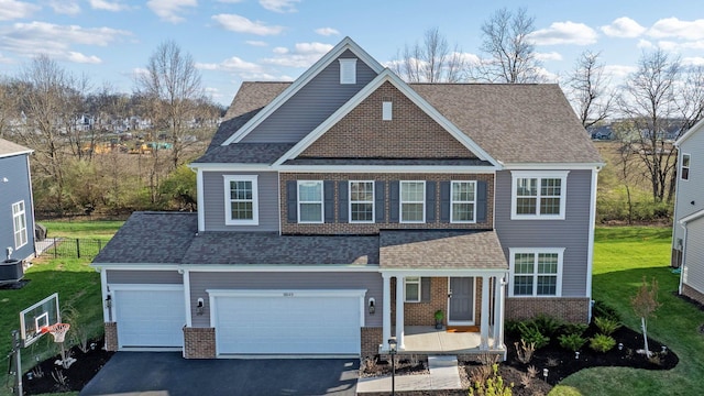 craftsman-style home featuring aphalt driveway, covered porch, a front yard, fence, and brick siding