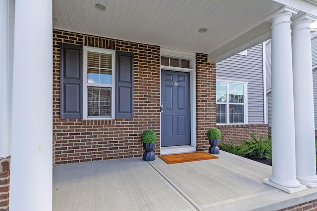 entrance to property featuring brick siding and covered porch
