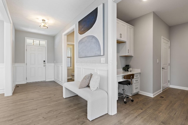 mudroom with light wood-style floors and built in desk