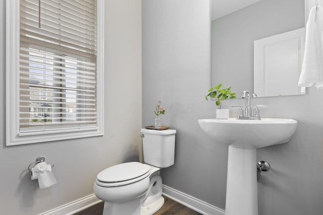 half bath featuring toilet, wood finished floors, and baseboards