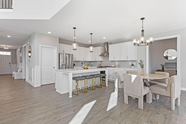 dining space with light wood-style flooring, a notable chandelier, wainscoting, and recessed lighting