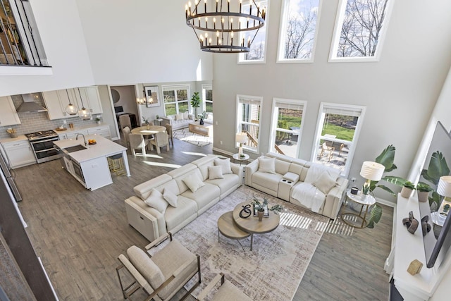 living room with dark wood-style floors, a notable chandelier, a towering ceiling, and a healthy amount of sunlight