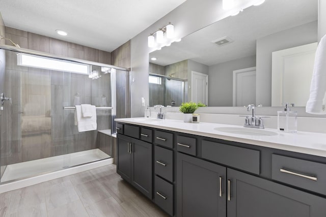 full bath featuring a sink, visible vents, double vanity, and a stall shower