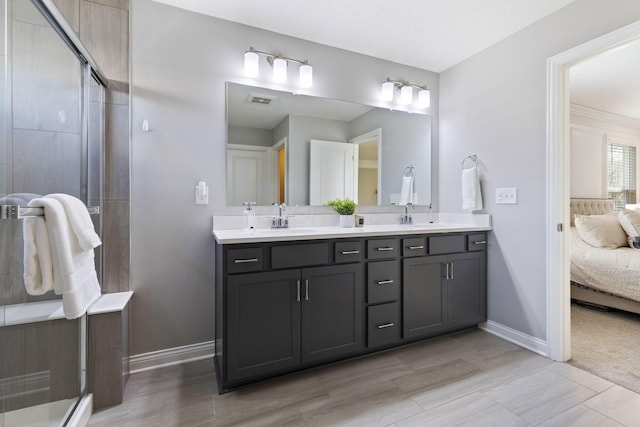 bathroom featuring baseboards, double vanity, ensuite bath, visible vents, and a sink
