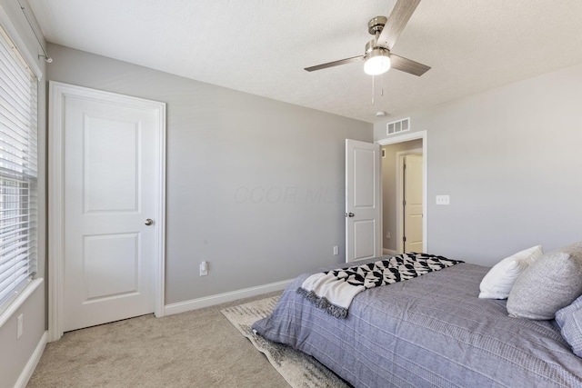 bedroom with visible vents, baseboards, a ceiling fan, and light carpet
