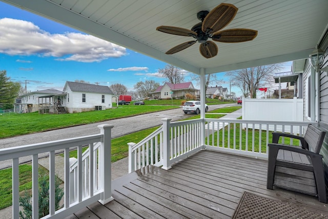 deck featuring ceiling fan, a residential view, a yard, a porch, and central AC unit
