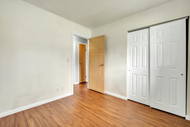 unfurnished bedroom with a closet, light wood-style flooring, and baseboards