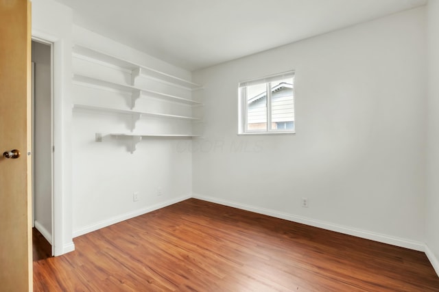 spare room with baseboards and wood finished floors