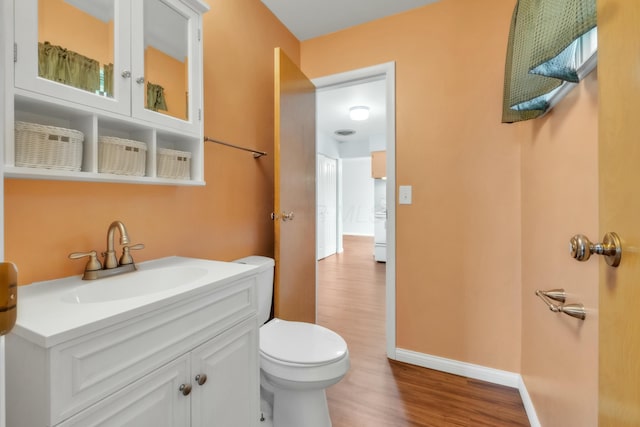 bathroom featuring toilet, vanity, wood finished floors, and baseboards