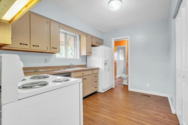 kitchen with white appliances, light wood-style flooring, light countertops, a sink, and baseboards