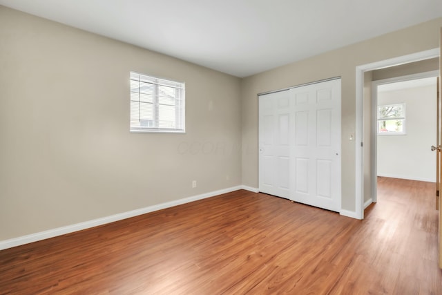 unfurnished bedroom with a closet, light wood finished floors, and baseboards