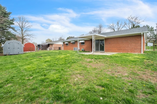 back of property featuring a lawn, brick siding, a storage shed, and an outbuilding
