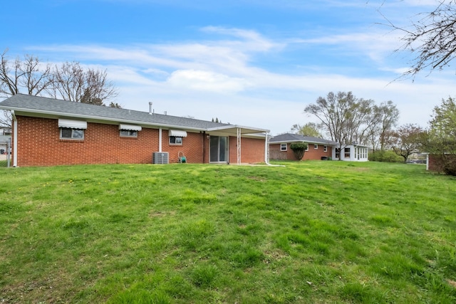 back of property featuring central air condition unit, brick siding, and a lawn