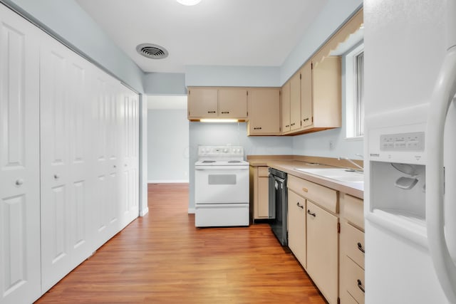 kitchen with white appliances, light wood-style flooring, cream cabinets, visible vents, and a sink