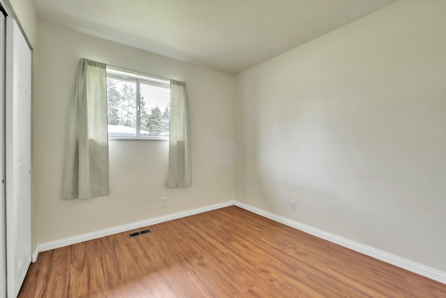 empty room with visible vents, baseboards, and wood finished floors