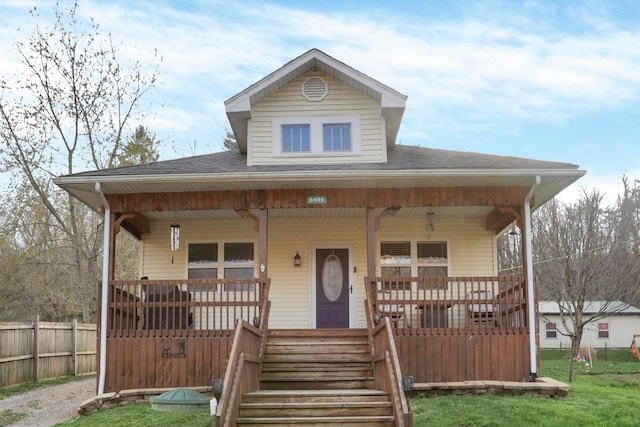 view of front of property featuring roof with shingles, a porch, and fence