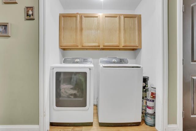 clothes washing area featuring separate washer and dryer, wood finished floors, and cabinet space