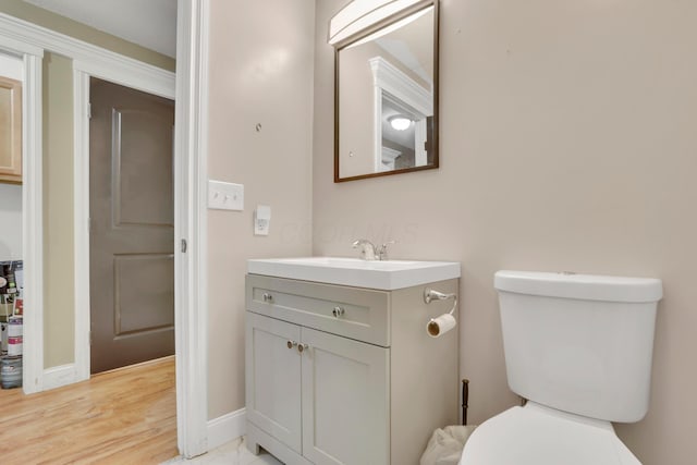 half bathroom with vanity, baseboards, and toilet