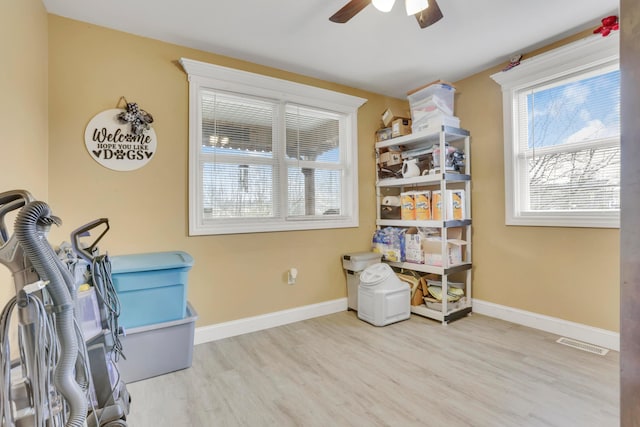 interior space with wood finished floors, ceiling fan, baseboards, and visible vents