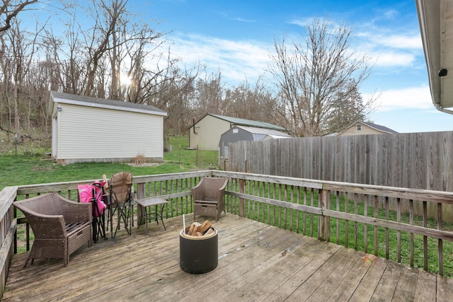 wooden deck featuring an outbuilding, fence, a yard, and a storage unit