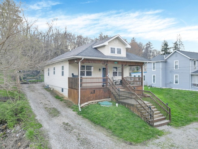 bungalow featuring stairway, a front yard, roof with shingles, and covered porch