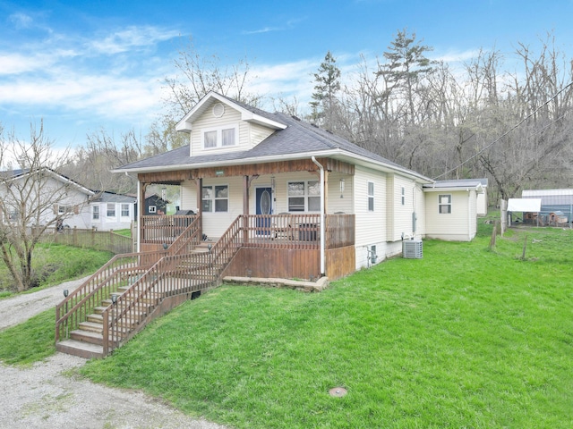 view of front of house featuring cooling unit, a front lawn, stairs, a shingled roof, and covered porch