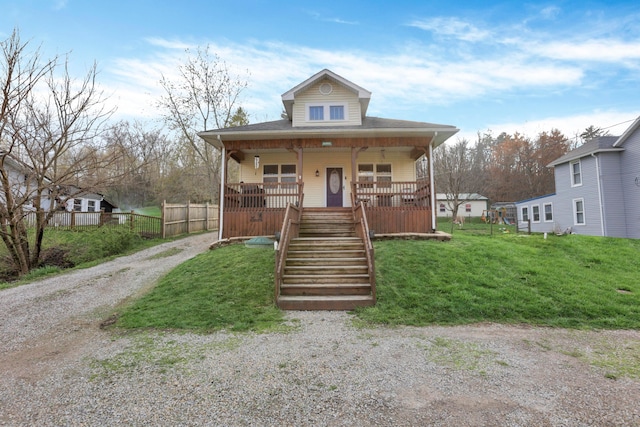 bungalow with driveway, a front yard, stairs, fence, and covered porch
