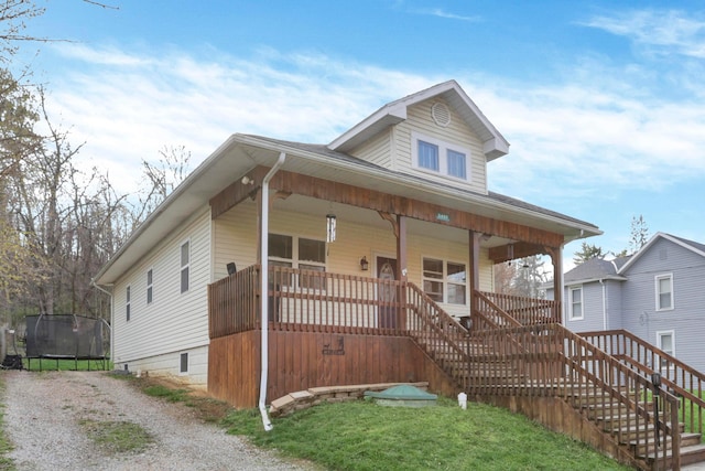 bungalow-style house with a trampoline, covered porch, and stairway