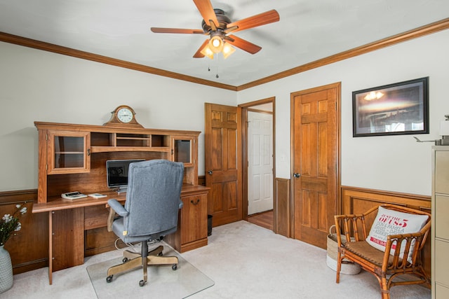home office featuring crown molding, wainscoting, wooden walls, ceiling fan, and light colored carpet
