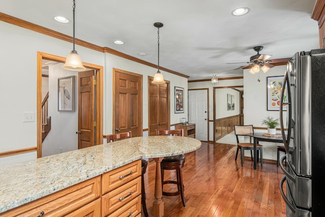 kitchen featuring hanging light fixtures, freestanding refrigerator, ceiling fan, ornamental molding, and wood-type flooring