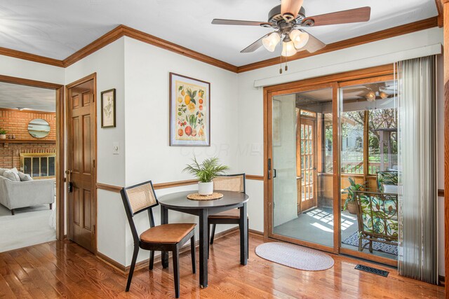dining area with baseboards, visible vents, a ceiling fan, crown molding, and hardwood / wood-style flooring