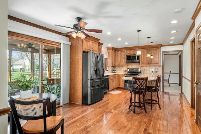 kitchen with brown cabinetry, ceiling fan, appliances with stainless steel finishes, and tasteful backsplash