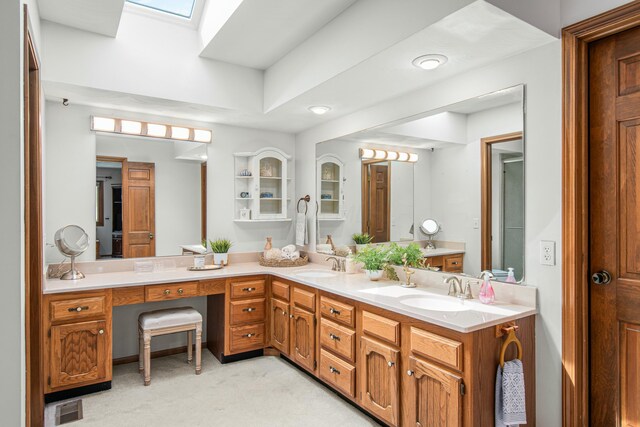 full bathroom with double vanity, visible vents, a skylight, and a sink