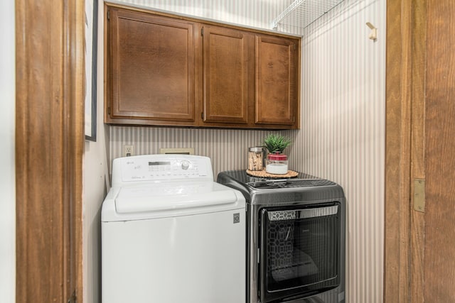 washroom with washer and dryer, cabinet space, and wallpapered walls
