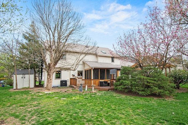 rear view of property featuring central AC unit, a storage shed, stucco siding, an outbuilding, and a sunroom