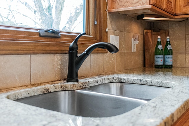 room details with light countertops, brown cabinets, decorative backsplash, and a sink