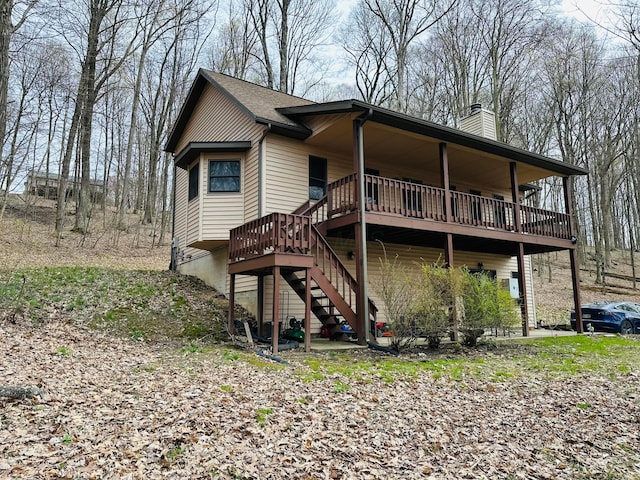 rear view of house featuring a chimney, a wooden deck, and stairway