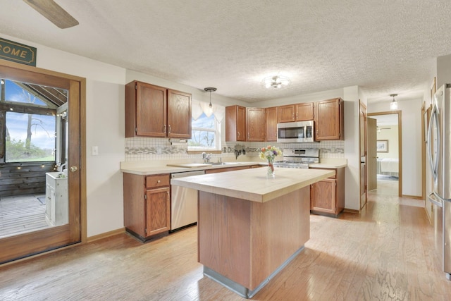 1649 Loudon St, Granville, OH 43023 - kitchen featuring a textured ceiling, light wood-style floors, stainless steel appliances, backsplash, and a kitchen island