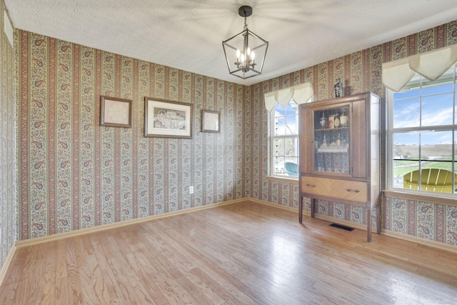 1649 Loudon St, Granville, OH 43023 - unfurnished dining area with a notable chandelier, wallpapered walls, wood finished floors, and visible vents