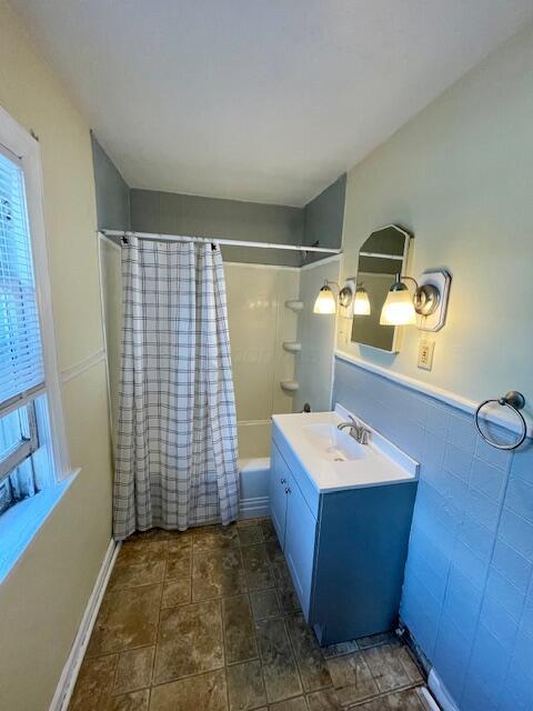bathroom with a wealth of natural light, vanity, and shower / bath combination with curtain