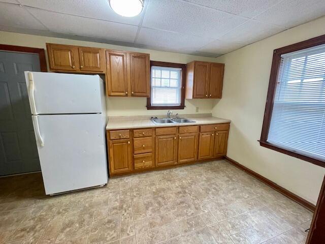 kitchen featuring a sink, brown cabinets, and freestanding refrigerator