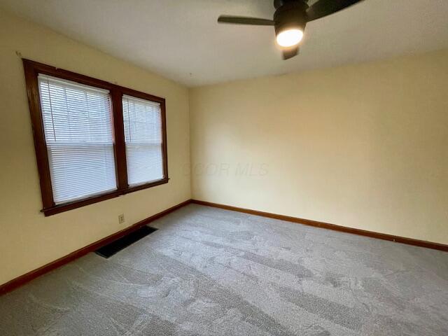 spare room featuring visible vents, a ceiling fan, baseboards, and carpet floors