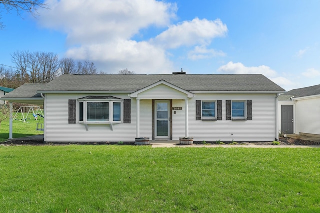 ranch-style home with a shingled roof, a front lawn, and a playground