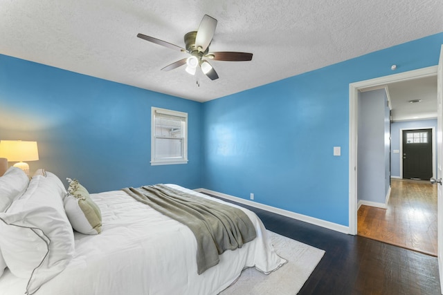 bedroom featuring baseboards, a ceiling fan, wood finished floors, and a textured ceiling