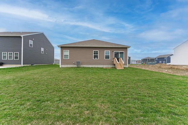 back of property with entry steps and a yard